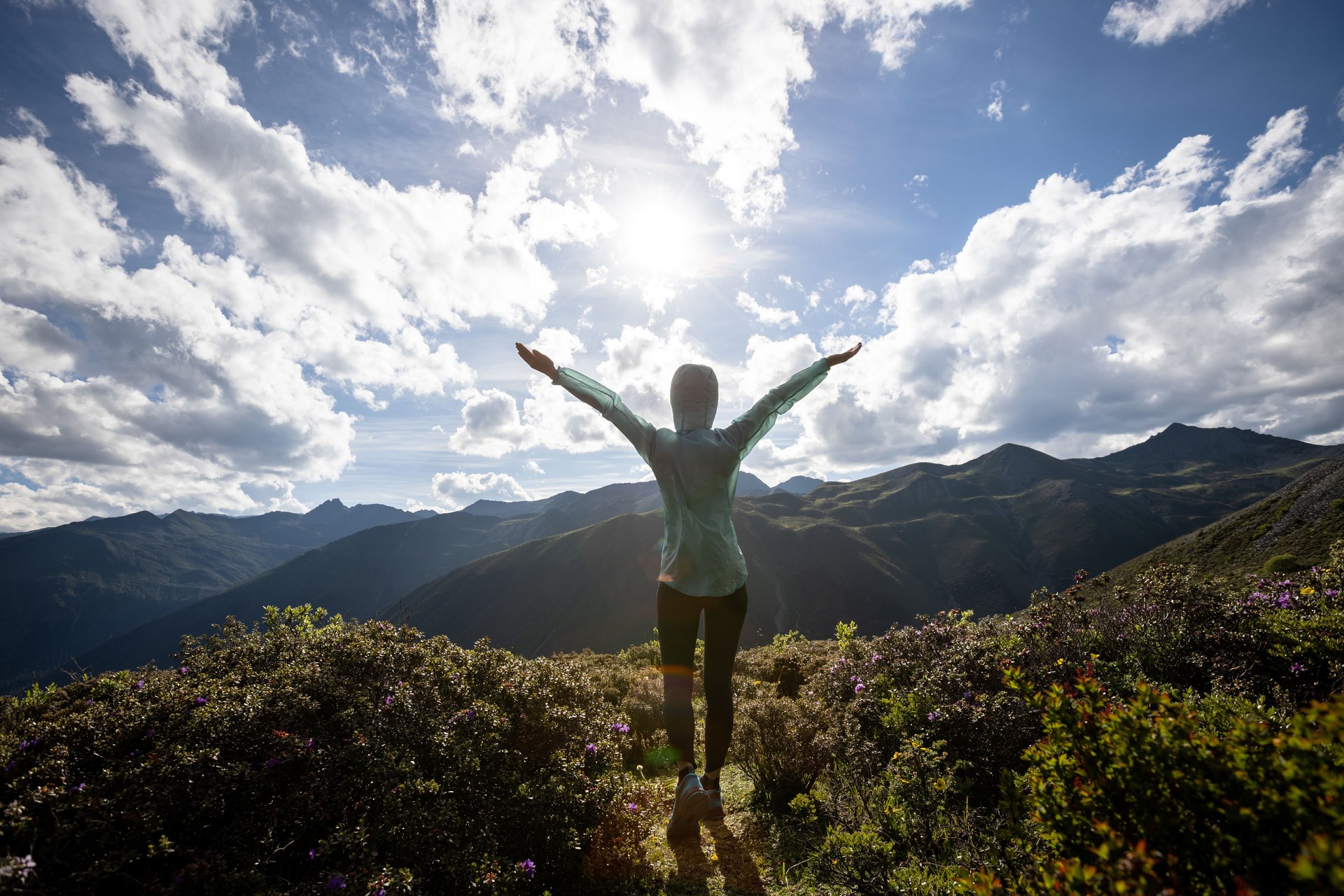 Successful woman outstretched limbs at high altitude mountain peak